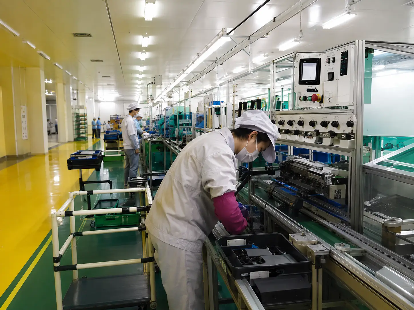 Worker operating equipment on an automotive AC parts production line